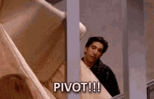 A GIF of a clip from the TV show Friends. Ross and an unseen Friend are trying to get a couch up the stairs and Ross is shouting “PIVOT!!”